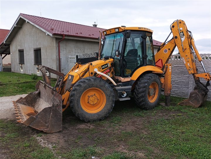 Traktorbager JCB pri práci na pozemku